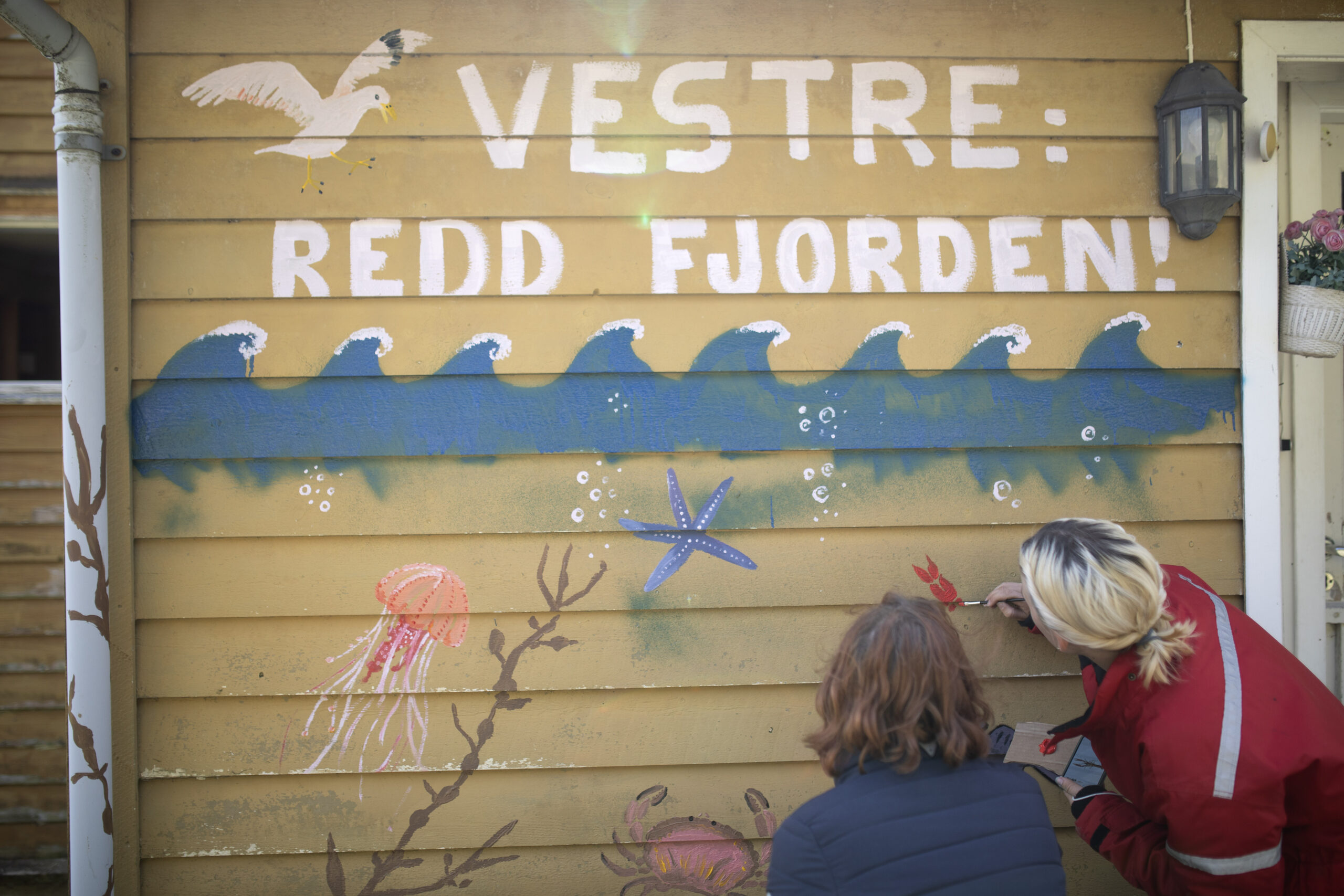 Marah van Andel og Gina Gylver dekorer fremsiden av Engebøhuset, med et tydelig budskap til næringsminister Jan CHristian Vestre.